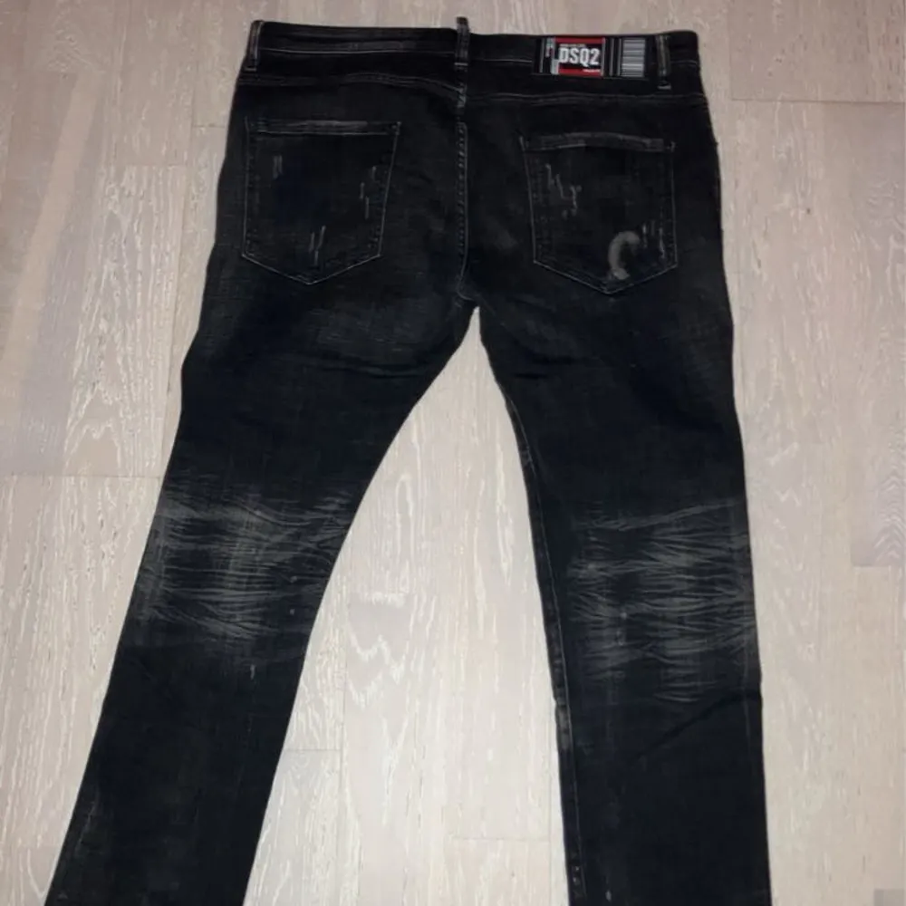 Säljer ett par svarta jeans från DSQ2 i bra skick. De har coola slitningar och en unik tvättad look. Perfekta för en avslappnad stil med en edgy touch. Passar både till vardags och fest!. Jeans & Byxor.