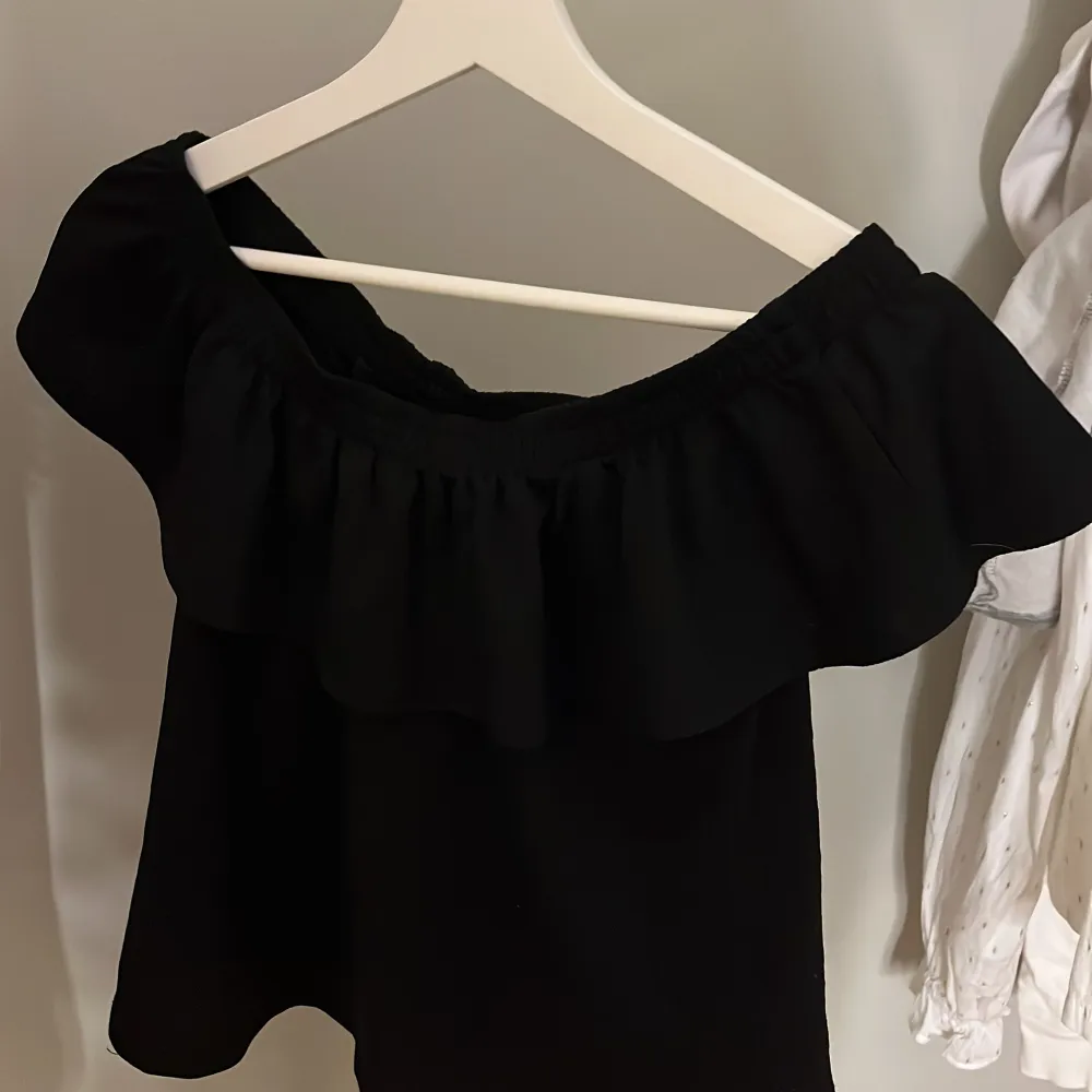 Snygg svart offshoulder topp från Gina Tricot i storlek S. Perfekt för sommarens fester med sin eleganta volangdetalj. Toppen är i mycket bra skick och ger en chic look till vilken outfit som helst.. Toppar.