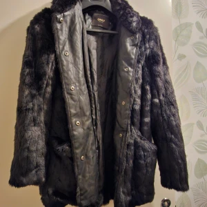 Svart pälsjacka superfin helt ny - Säljer en supermjuk och fluffig svart pälsjacka.. Perfekt för att hålla sig varm och stilren under kalla dagar. Jackan har långa ärmar och stängs med knappar framtill. Den är i mycket bra skick och redo för nya äventyr!