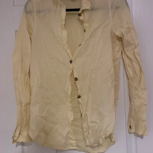 Gul skjorta från Divided - Säljer en ljusgul skjorta från Divided med knappar framtill. Skjortan har långa ärmar och en klassisk krage. Perfekt för en stilren look. Strlk 34