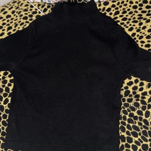 Svart polotröja - Säljer en stilren svart polotröja med lång ärm. Perfekt för kyligare dagar och enkel att matcha med olika outfits. Tröjan har en klassisk design med ribbad struktur.