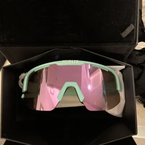 Mintgröna sportglasögon från Bliz - Snygga sportglasögon från Bliz i en mintgrön färg med rosa spegelglas. Perfekta för utomhusaktiviteter och träning. Glasögonen är riktigt sköna och ger ett bra skydd mot solen!!! 