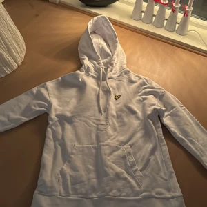 Vit hoodie från lyle & scott  - Säljer en stilren vit hoodie från lyle & scott. Hoodien har en klassisk design med känguruficka och justerbar huva. Perfekt för en avslappnad look.
