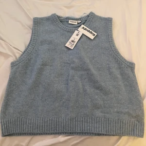Ljusblå stickad väst från Kappahl - Säljer en ljusblå stickad väst från Kappahl. Aldrig använd. Västen har en ribbad kant vid ärmhålen och nederkanten, vilket ger en snygg och stilren look. Perfekt för lager-på-lager under kyligare dagar.