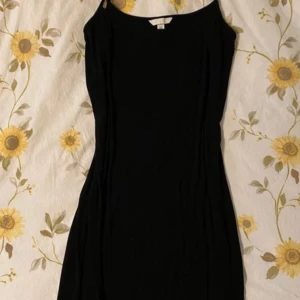 Svart klänning från H&M - Snygg svart klänning från H&M med en enkel och elegant design. Klänningen har en smickrande passform och är perfekt för olika tillfällen. Den är ärmlös och har en klassisk stil som aldrig går ur mode.