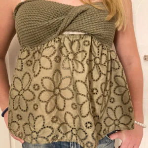 Grön tubtopp med blommönster - Snygg grön tubtopp med ett stickat överdel och ett blommigt mönster på den nedre delen. Toppen har en twistdetalj framtill och smala axelband. Perfekt för en somrig look! Kan sänka priset! 💕