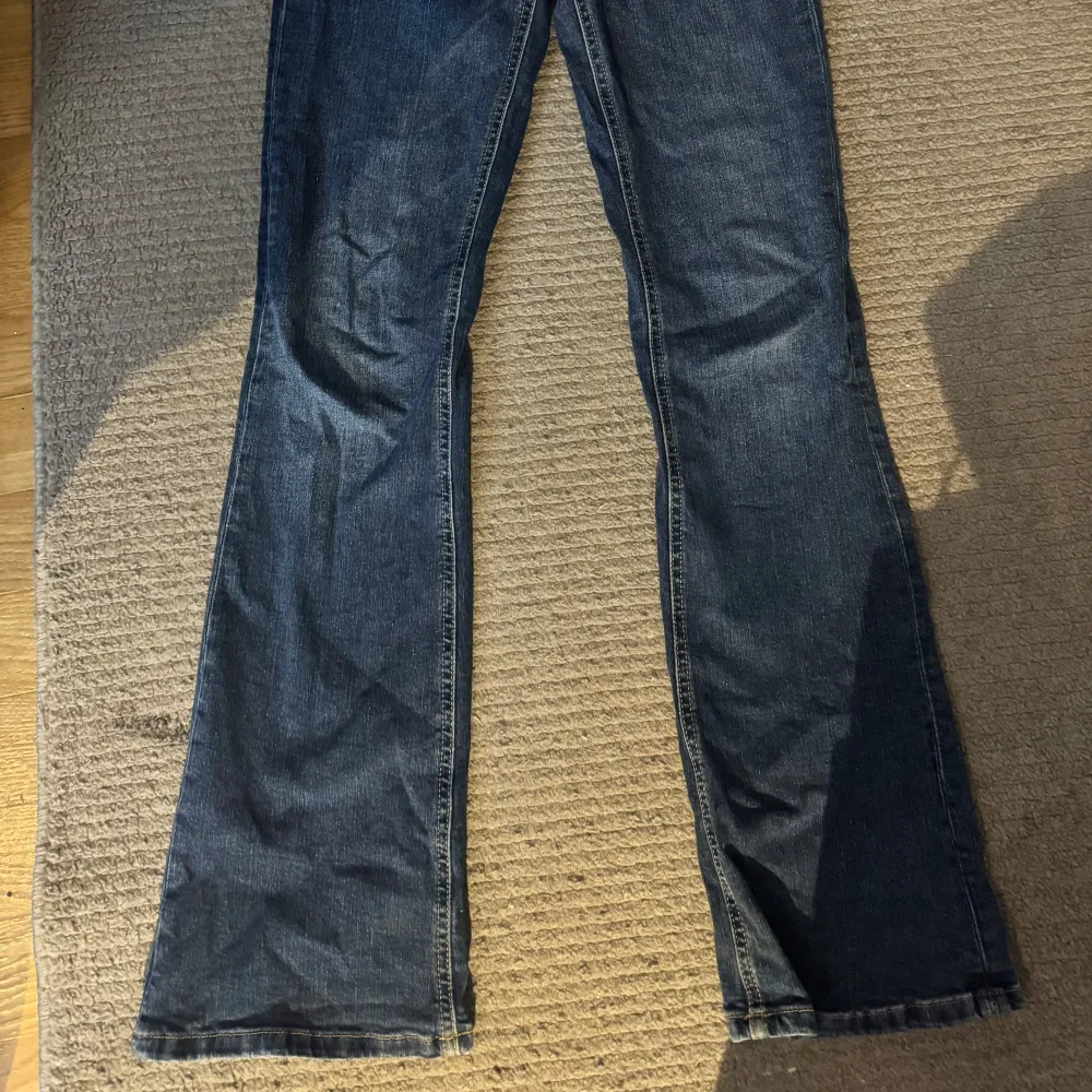 Snygga blå jeans med bootcut-stil och klassisk femficksdesign. Perfekta för en avslappnad look. De har en bekväm passform och är tillverkade i ett slitstarkt denimtyg.. Farkut & Housut.