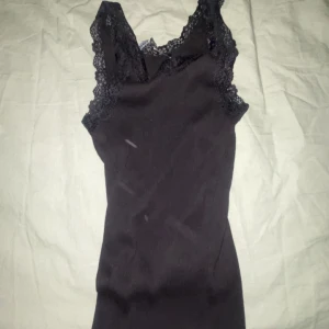 Svart linne med spetsdetaljer - Snygg svart linne med spetsdetaljer vid axlarna. Perfekt för en elegant look. Linnet är ärmlös och har en smickrande passform.