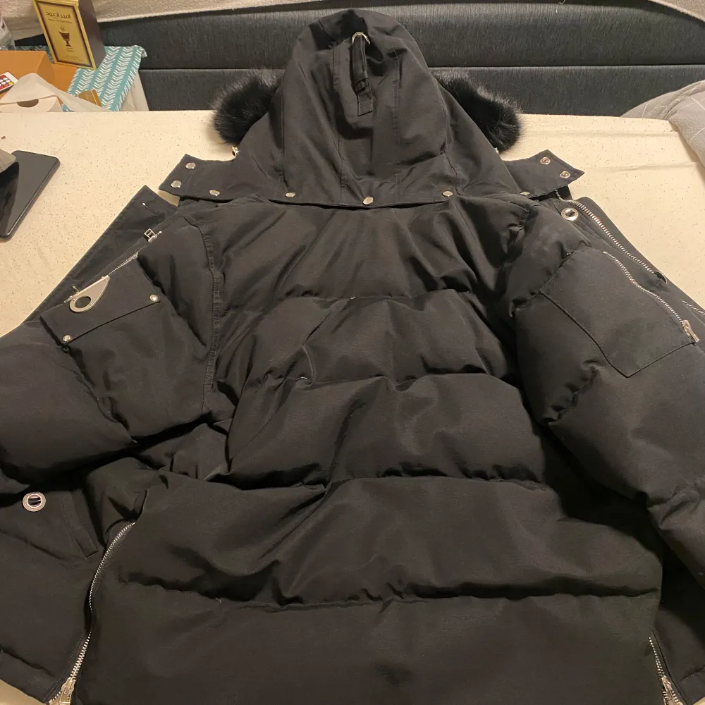 PRIS KAN DISKUTERAS Snygg svart dunjacka från Moose Knuckles med pälskantad huva och flera praktiska fickor. Jackan har dragkedja och knappar framtill samt långa ärmar. Perfekt för vintern storleken är XL men passar alla. Takit.