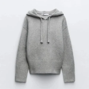 Grå stickad hoodie Zara  - Mysig grå stickad hoodie med ribbade muddar och justerbar huva. Perfekt för kyliga dagar och ger en avslappnad stil. Passar bra till jeans eller leggings.
