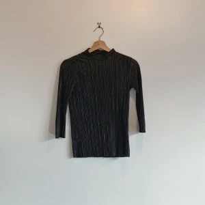 Svart ribbad topp från Reserved - Säljer en stilren svart ribbad topp från Reserved i storlek XS. Toppen har långa ärmar och en elegant design som passar perfekt till olika tillfällen. Materialet är mjukt och följsamt.