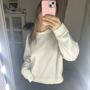 Vit sweatshirt - Säljer en vit sweatshirt med normal passform. Tröjan har långa ärmar och en klassisk rund halsringning. Perfekt för en avslappnad stil.