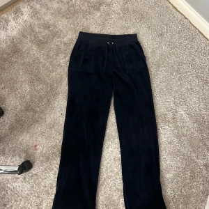 Mörkblå mjukisbyxor från Juicy Couture - Säljer ett par mörkblå mjukisbyxor från Juicy Couture. Byxorna har en bekväm passform med snörning i midjan och praktiska fickor både fram och bak. Perfekta för en avslappnad stil.