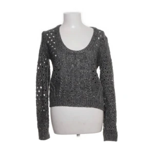 Grå stickad tröja från Pepe Jeans - Snygg grå stickad tröja från Pepe Jeans med ett unikt hålmönster. Tröjan har långa ärmar och en rund halsringning, perfekt för kyligare dagar. Den är både stilren och bekväm.