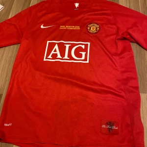 Röd Manchester united retro Ronaldo fotbollströja från Nike  - Säljer en röd fotbollströja från Nike med tryck av AIG och klubbmärke på bröstet. Tröjan har texten 'FINAL MOSCOW 2008' och spelarens namn och nummer på ryggen. Perfekt för fotbollsfans! Player fit så den passar både m och s