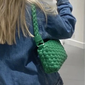 Grön flätad vävd axelväska - Snygg grön axelväska med flätad vävd design och dragkedja. Perfekt för att ge en färgklick till din outfit. Väskan har ett rymligt fack och en bekväm axelrem. Finns fläckar inuti sen tidigare ägare men inget som stört mig alls🥰