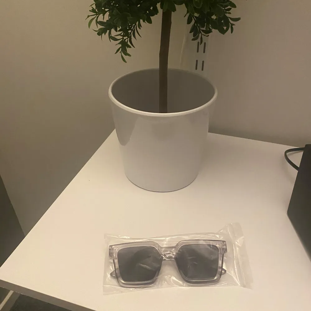 Snygga solglasögon med transparent båge och fyrkantig form. Perfekta för en stilren look. De mörka glasen ger ett coolt intryck och skyddar mot solen. Passar både till vardag och speciella tillfällen. Asusteet.