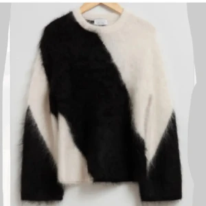 Svart och vit fluffig tröja från Other Stories  - Säljer en unik och stilren svart och vit tröja från other stories. Helt ny och extremt snygg.. Tröjan har en fluffig textur och ett asymmetriskt mönster som ger en modern look. Perfekt för att hålla sig varm och trendig under kyliga dagar.