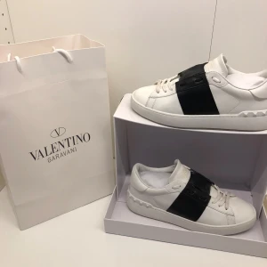 Valentino open  - Ett par äkta vita valentino open med svart streck för 2899 ny pris är 7280kr. Dom är i storlek 42 passar 43 och är i 8,5/10 skick boxen är lite skadad och så är dom ba lite smutsig bara och allt du ser i bilderna kommer med. Pris kan diskuteras och skriv om du har några frågor eller vill ha bild på något specifikt.