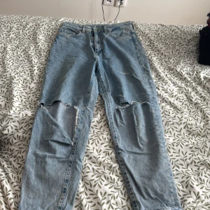 Blå loose mom jeans - Säljer ett par blå loose mom jeans från &Denim. De har en ultra hög midja och är i ankellängd. Byxorna har slitningar på knäna för en trendig look. Perfekta för en avslappnad stil.