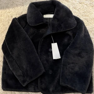 Svart pälsjacka från Arket - Säljer en snygg mörkgrå pälsjacka från Arket. Helt ny och oanvänd. Perfekt för att hålla sig varm! 💞Nypris = 2290
