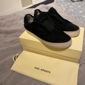 Axel Arigato - Ett par schyssta skor från Axel Arigatos laceless i svart, de är använda men är fortfarande i mycket bra skick, de enda som är litet är hälarna där jag har satt lagningslappar, box och dustbag medföljer, vid frågor är de bara att höra av sig. Mvh Max