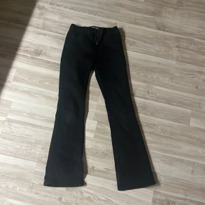 Svarta bootcut byxor - Snygga svarta bootcut byxor med klassisk design. De har en knapp och dragkedja framtill samt fickor bak. Perfekta för en stilren look.