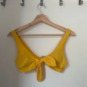 Gul bikiniöverdel med knyt - Snygg gul bikiniöverdel med knyt framtill. Perfekt för soliga dagar på stranden eller vid poolen. Den har breda axelband och en stilren design som ger en bekväm passform.