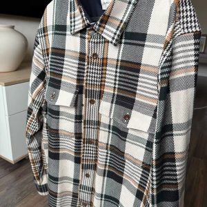 Rutig overshirt från GANT - Säljer en snygg rutig overshirt från GANT i beige, svart, grön och orange. Den har långa ärmar och knappar framtill samt två bröstfickor. Perfekt för lager-på-lager-stilen! Köpt från thernlunds för 1700. 