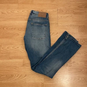 Blå jeansbyxor från Smog - Snygga blå jeansbyxor från Smog med klassisk femficksdesign och en bekväm passform. Byxorna har en medelhög midja och en rak stil som passar perfekt till vardags. De är tillverkade i slitstarkt denim och har en snygg tvättad look. Skriv om ni har funderingar och priset är inte hugget i sten!