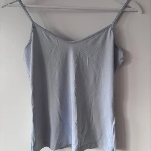 Ljusblå linnetopp - Säljer en enkel och stilren ljusblå linnetopp med smala axelband. Perfekt för varma dagar eller som ett basplagg i garderoben. Är lite små-nopprig som det visas på bild, annars inga defekter! 