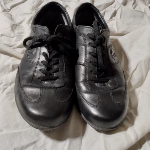 Svarta skinnskor från Ecco - Snygga svarta skinnskor från Ecco med snörning. Perfekta för en stilren look. Skorna har en bekväm passform och slitstark sula. Ecco-logotypen syns diskret på sidan och sulan.