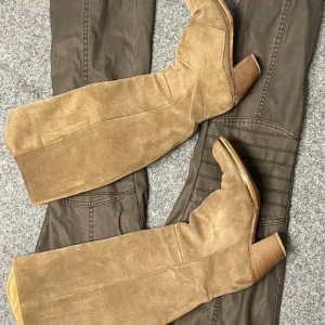 Beige mockastövlar från Acne - Snygga beige stövlar i mocka från Acne med en robust klack. Perfekta för att ge en stilren touch till din outfit. De har en klassisk design som passar till många tillfällen.