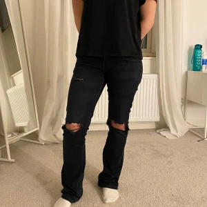 Svarta jeans med slitningar - Snygga svarta jeans med slitningar på knäna som jag själv gjort. De är lågmidjade, bootcut och är från ltb.  Innerbenslängden är 74cm och midjemåttet är cirka 38cm (25/30)