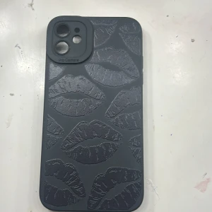 Svart mobilskal med läppmönster - Snyggt svart mobilskal med ett coolt läppmönster i relief. Skalet är designat för att passa en telefon med Pro Camera. Perfekt för att ge din mobil en unik look och extra skydd.