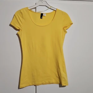 Gul kortärmad topp - Säljer en solgul kortärmad topp med rund halsringning. Perfekt för sommardagar och enkel att matcha med olika outfits. Tillverkad i Turkiet.