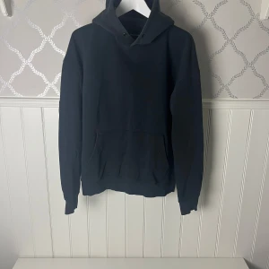Svart hoodie från Jack & Jones - Säljer en stilren svart hoodie från Jack & Jones. Den har en klassisk design med en stor ficka framtill och en bekväm huva. Perfekt för en avslappnad look.