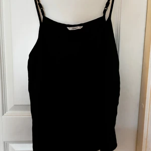 Svart linnetopp från ONLY - Snygg svart linnetopp från ONLY med smala axelband. Perfekt för en stilren look. Passar bra till både jeans och kjol.