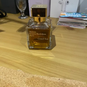Grand Soir från Maison Francis Kurkdjian - Elegant parfymflaska från Maison Francis Kurkdjian med doften Grand Soir. Flaskan är fyrkantig med en gyllene kork och rymmer 70 ml. Förpackningen är stilren i vitt och guld. Har haft den i ett år och använt 5 spray. Priset är inte hugget i sten.