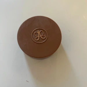 Cream Bronzer Cool Brown - Säljer en Cream Bronzer i färgen Cool Brown från Anastasia Beverly Hills. Perfekt för att skapa en naturlig solkysst look. Kommer i en snygg brun burk med logotyp på locket.