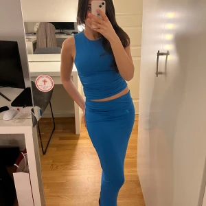 Blå ärmlös topp med maxi kjol - Snygg blå ärmlös klänning i tvådelad design med en tight passform. Perfekt för en stilren look. Materialet är mjukt och stretchigt för extra komfort.