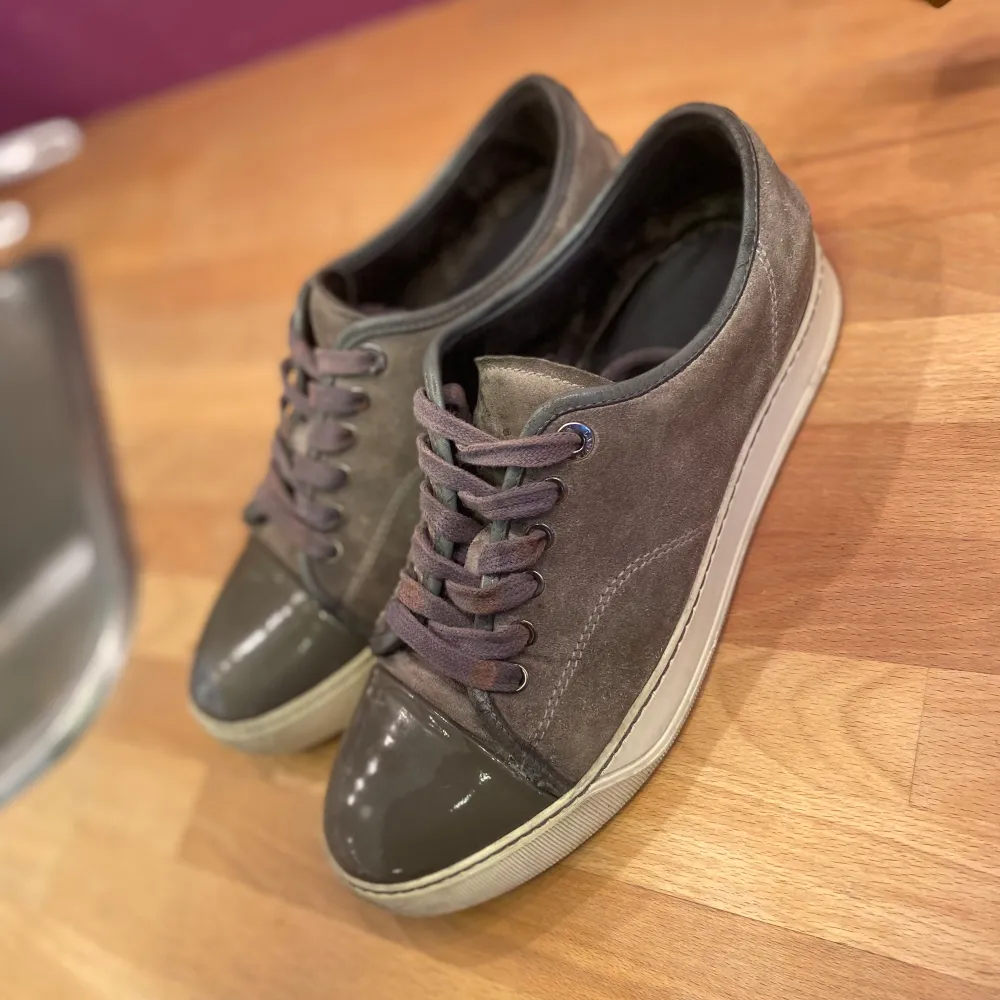 Snygga grå sneakers med en glansig tå i mörk grön och snörning. Skorna har en stilren design med en vit sula som ger en modern touch. Perfekta för en avslappnad stil. (Äkta) pris går att diskutera . Kengät.