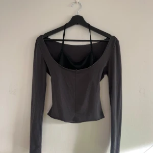 Grå långärmad topp - Snygg grå långärmad topp med djup urringning och tight passform. Perfekt för en stilren look. 