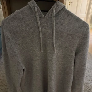 Grå hoodie kashmir blend  - Säljer en stilren grå hoodie med långa ärmar och justerbar huva. Perfekt för en avslappnad look. Passar bra till både jeans och mjukisbyxor.