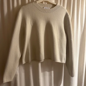 Beige tröja från & Other Stories - Säljer en stilren beige tröja från & Other Stories. Tröjan har en rund hals och långa ärmar, perfekt för en minimalistisk look. Tillverkad i ett mjukt material som ger en skön känsla. Säljer då den har blivit för liten, upplever att den är ganska liten i storleken