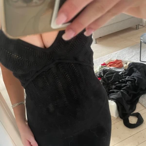 Svart klänning med smala axelband - Snygg svart klänning med smala axelband och v-ringad design. Klänningen har en åtsittande passform och ett subtilt mönster som ger en elegant touch. Perfekt för en kväll ute eller en speciell tillställning. Köpt för 800