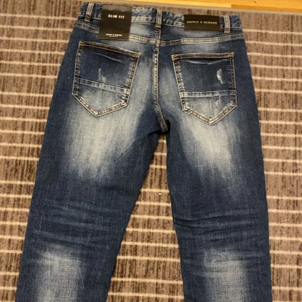 Snygga blå jeans med slitna detaljer från Supply & Demand. De har en slim fit passform och klassisk femficksdesign. Perfekta för en trendig look. Passar även M, köpte den men den passa inte och rev kvittot så kan inte lämna den pris kan diskuteras. Farkut & Housut.