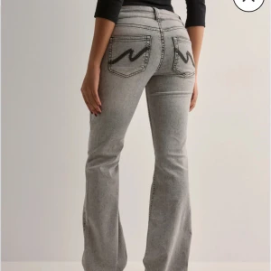 Grå jeans med broderade bakfickor - Snygga grå jeans med en cool broderad detalj på rumpan, säljer då dom är för stora Använda 3 gånger 
