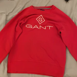 Röd tröja från GANT - Säljer en snygg röd tröja från GANT med deras ikoniska logga framtill. Tröjan har långa ärmar och en rund halsringning. Perfekt för en stilren look. Tröjan är i storleken S och sitter bra! Den är knappast använd. Pris kan diskuteras, gåva medföljer!😁🎁