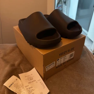 Yeezy Slide ”Soot” - Yeezy Slide ”Soot” Storlek: 10.5 US - 44,5 EU Skick: 8-9/10 (använd endast någon vecka under semester) Allt komplett med låda och kvitton. Pris 1500kr Mvh